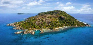 Aerial view of island surrounded by turquoise waters in the Seychelles
