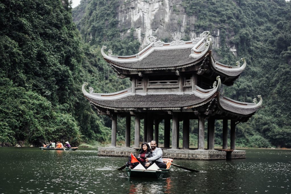 Couple on a boat tour passing a traditional pagoda in Vietnam