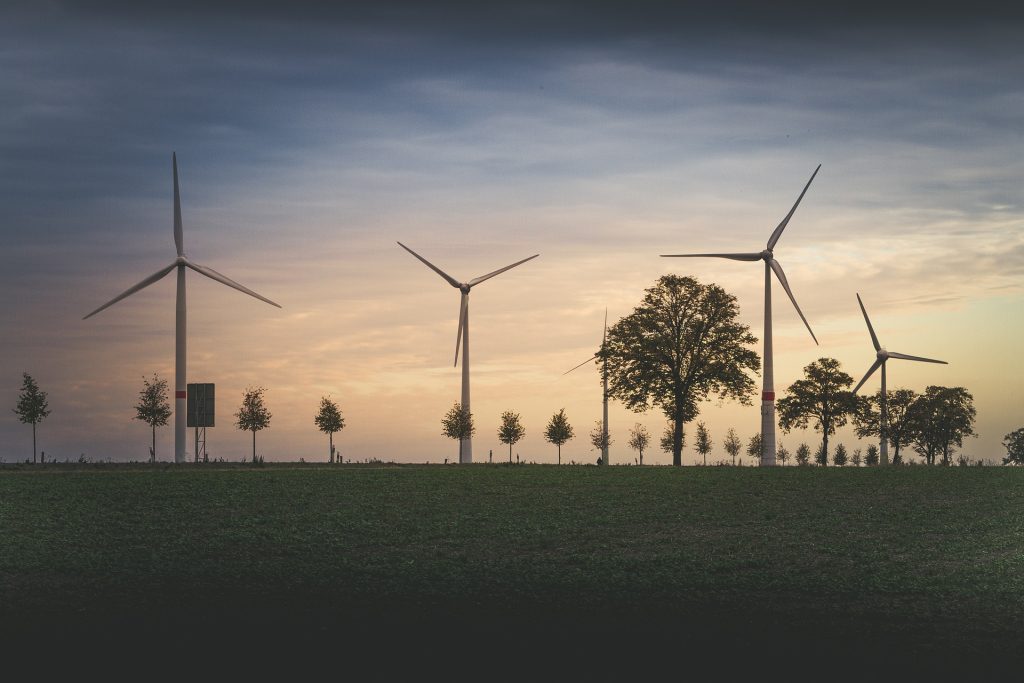 Wind turbines generating clean renewable energy across farmland at sunset