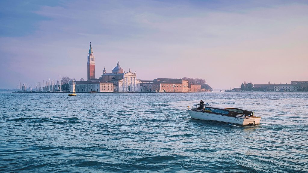 Motorboat crossing the Venice Lagoon with the city skyline at sunset
