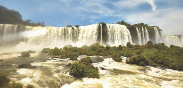 Panoramic view of a powerful waterfall cascading through a lush tropical landscape