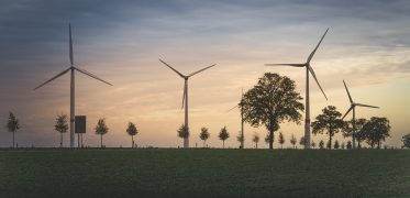 Wind turbines generating clean renewable energy across farmland at sunset