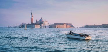 Motorboat crossing the Venice Lagoon with the city skyline at sunset
